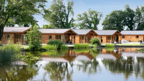 Bron Eifion Lodges, Criccieth - small wooden lodges wiht verandas around a reed lined lake edge