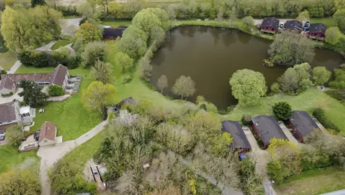 Otter falls devon - a drone shot over the lake lwith 6 lodges around the lake along with amture trees