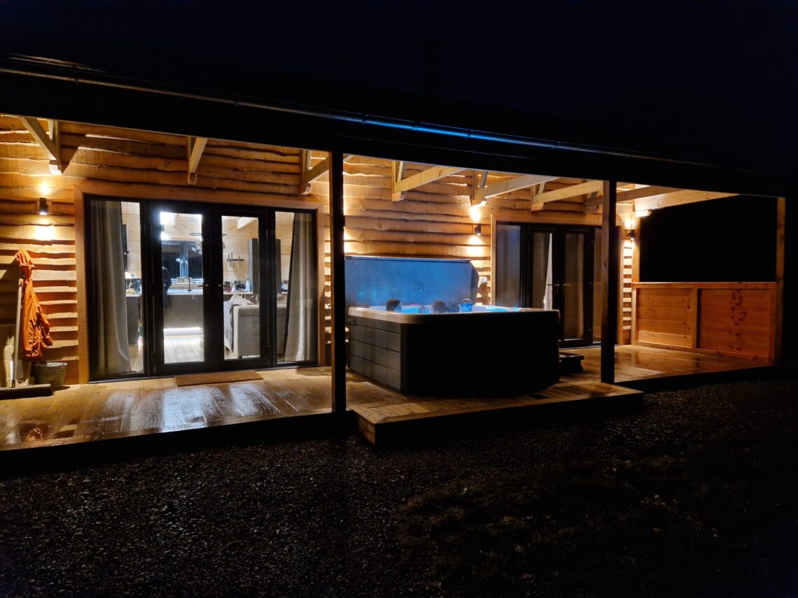 A lodge with an illminated hot tub in front