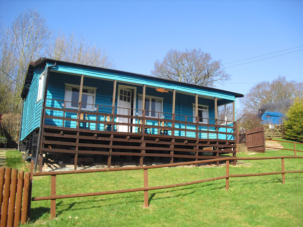 Barbel lodge on the banks of the Severn. A raise wooden lodge cabin painted a light blue sitting on a slope