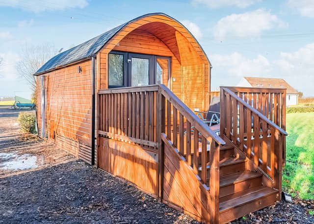 Fen View a shepherds hut made of pine with a decked area and stairs to the front