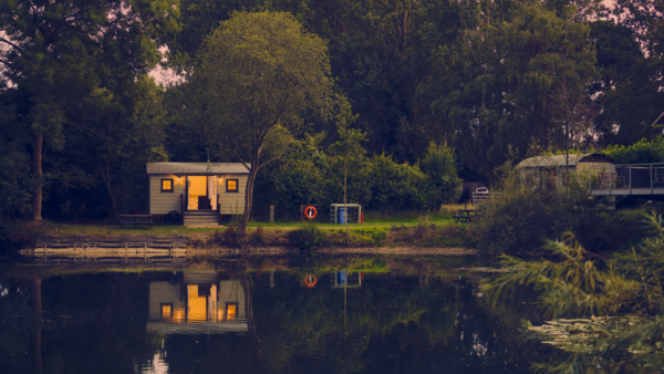 Westfield fishing lake at dusk with an iluminted shepherds hut on the bank