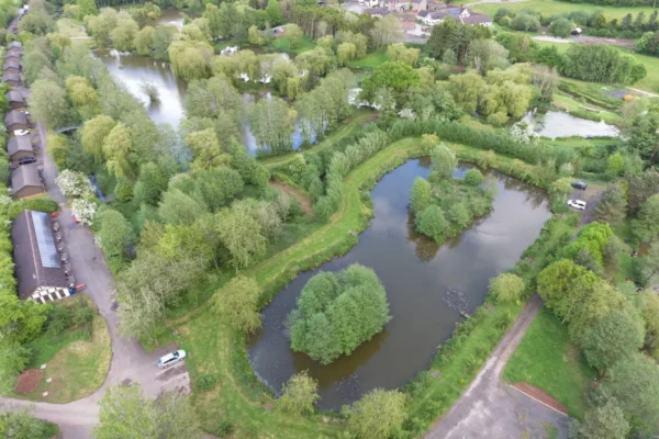 Drone shot of Docklows pools showing the lakes and a row of log cabins alongside a small road