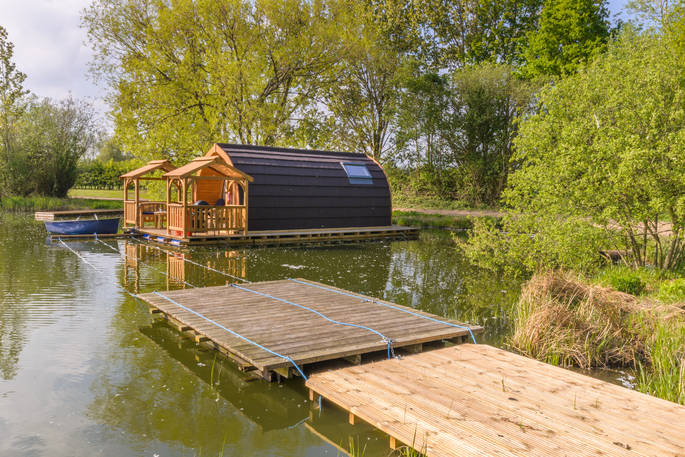 Floating glamping pod on a lake with decking around the sides