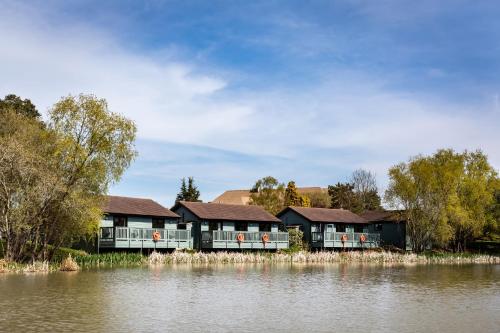 The vale - 3 mint green lodges alongside a reed lined lake