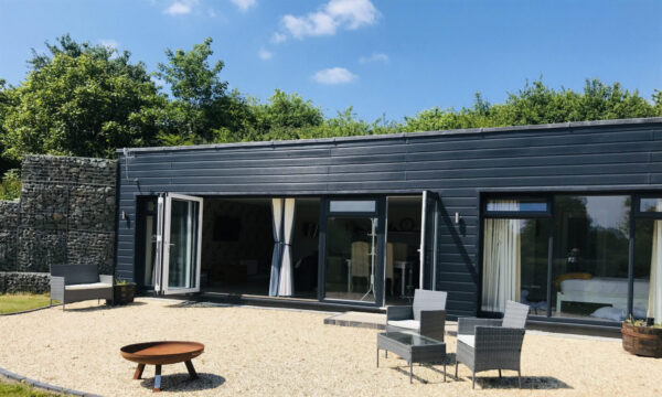 black eco fishing lodge with gravel in front and seating area