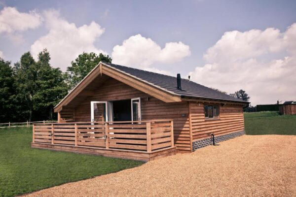 Wooden log cabin with wooden deck and fencing