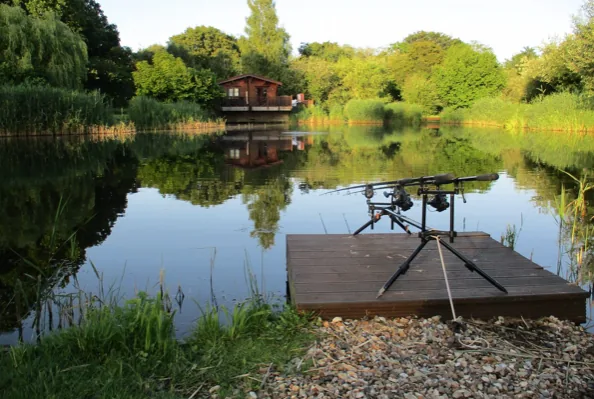 Carp rods set up on a private decked peg overlooking the lake at Badwell Ash Lodges, Suffolk