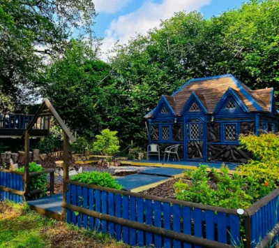 Blue timber Jack and Jill cabin with a shingle roof and garden at Colehurst Lake Lodges