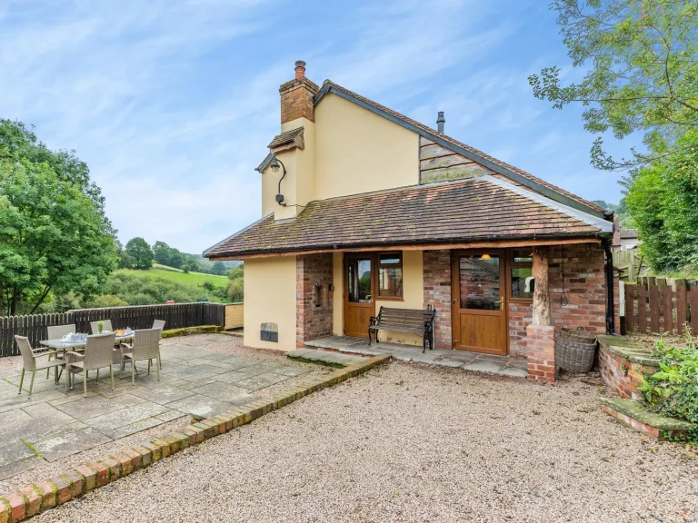 The Fishermans Retreat near Bewdley, a cream cottage with a patio dining set above the River Severn valley