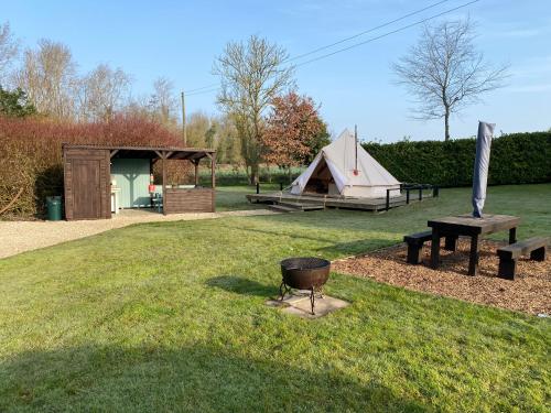 Bell tent glamping pitch with fire pit and picnic bench at Glen Farm, Norfolk