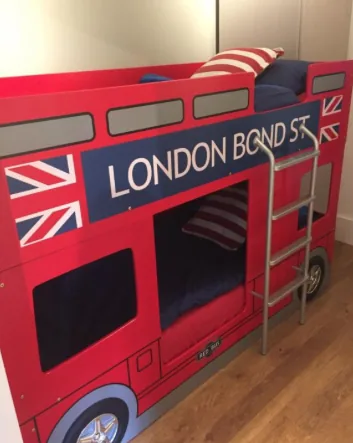 Red London bus themed bunk bed with ladder in a family lodge bedroom