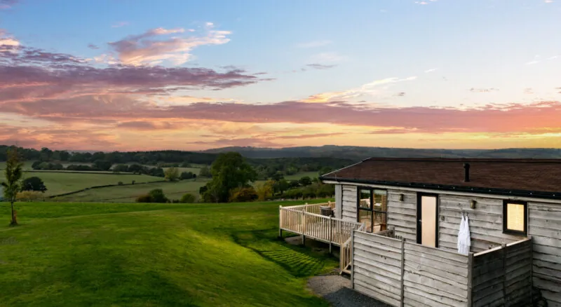 Timber lodge with decking and wide countryside views at Moonrise trout fishing lodges