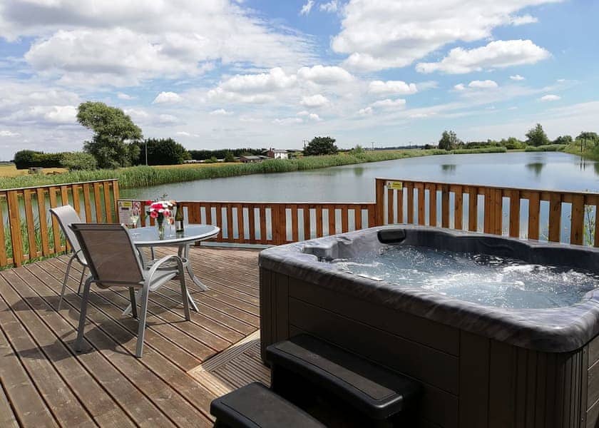 Hot tub on lodge decking overlooking a fishing lake, on the Norfolk fishing lodges guide