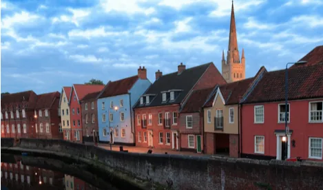 Colourful quayside houses beside the river in Norwich with the cathedral spire behind