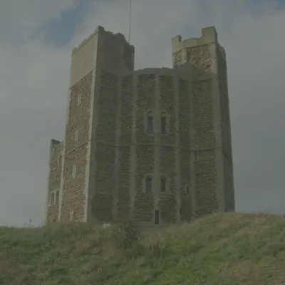 Orford Castle keep in Suffolk standing on a grassy mound under a pale sky
