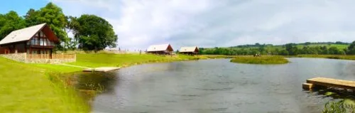 Lakeside lodges and a wooden jetty beside the fishing lake at Redewater