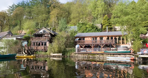 Timber lakeside lodges with balconies reflected in a wooded lake in Staffordshire