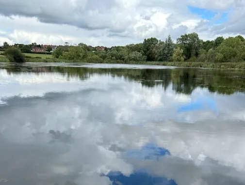 The large fishing lake at Steam Mill Lodges, Oakthorpe, with clouds reflected on still water