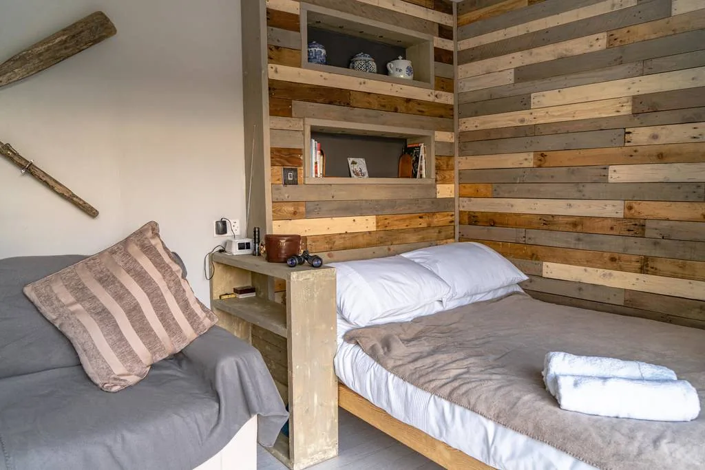 Cabin bedroom with reclaimed timber walls, double bed and folded towels