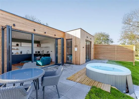 Modern timber lodge with hot tub and patio seating at Swanborough Lakes, Sussex