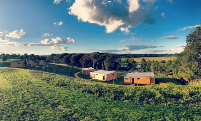 Timber lodges on a grassy slope overlooking the fishing lake at Swanborough Lakes, Lewes