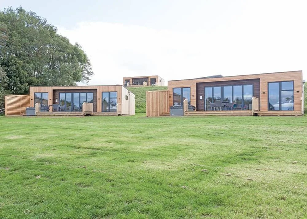 Modern timber-clad lodges with decking and glazed fronts at Swanborough Lakes, Sussex