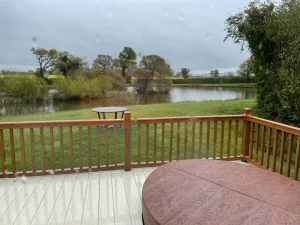 Lodge decking with a covered hot tub looking across the lake at Wigmore Lakes, Shropshire