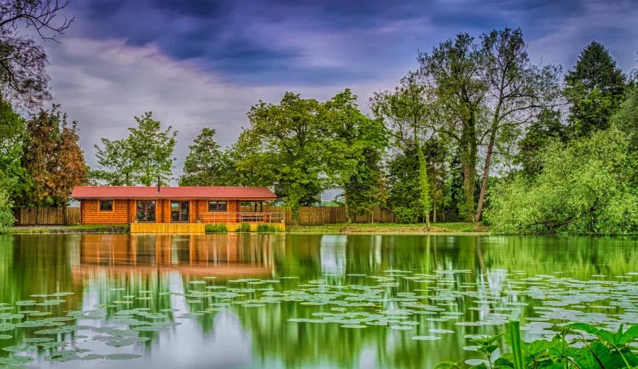Log fishing lodge with private pegs beside a lily covered lake at Willow Waters, Yorkshire