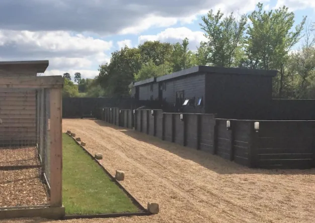 Row of dark clad lodges with private decking areas at Windsor Garden Lodge