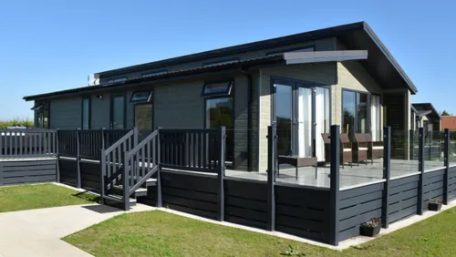 Black timber-clad lodge with glass-panelled decking at Wold View Country Park, Lincolnshire